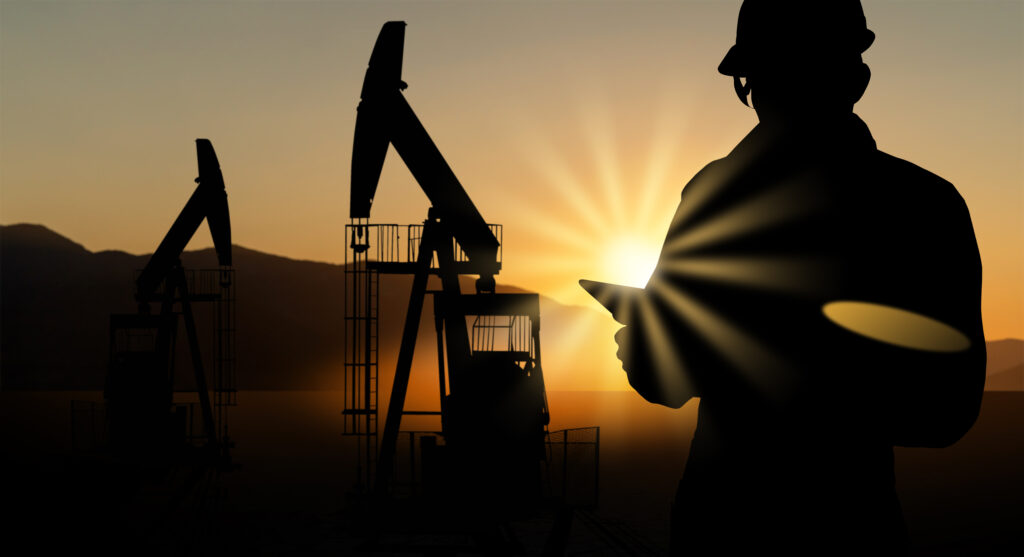 silhouette of engineer with a digital tablet on the background of oil rigs